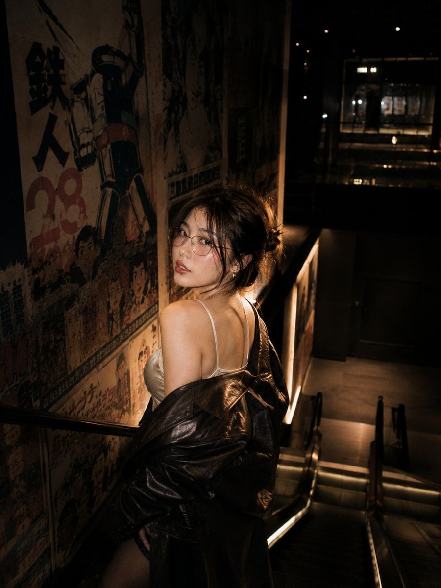 Cinematic nighttime portrait of a stylish young Asian woman standing on an escal