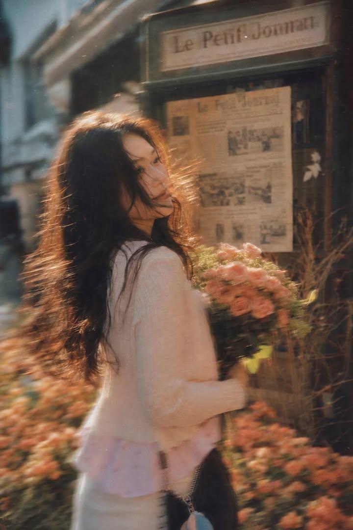 A beautiful young woman with long dark flowing hair holding a bouquet of soft pi