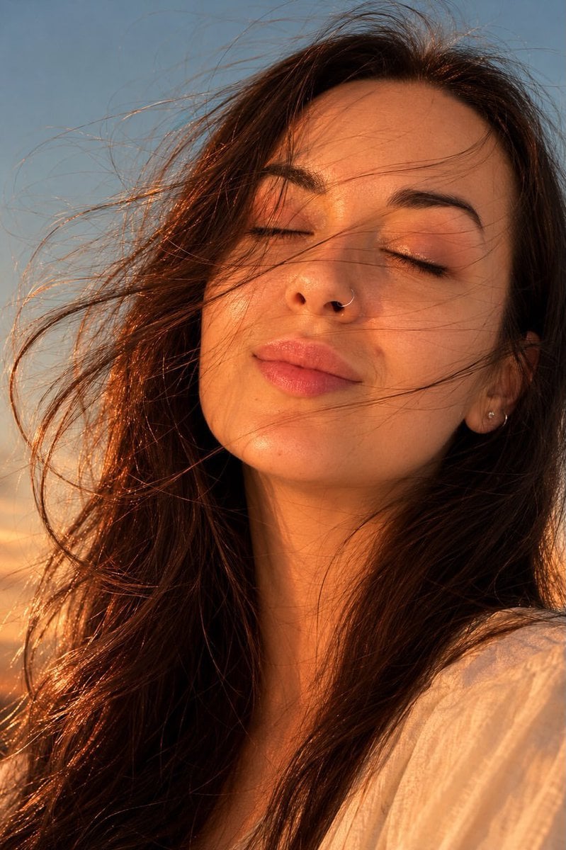 Ultra-realistic golden hour close-up portrait of a young woman outdoors, eyes ge