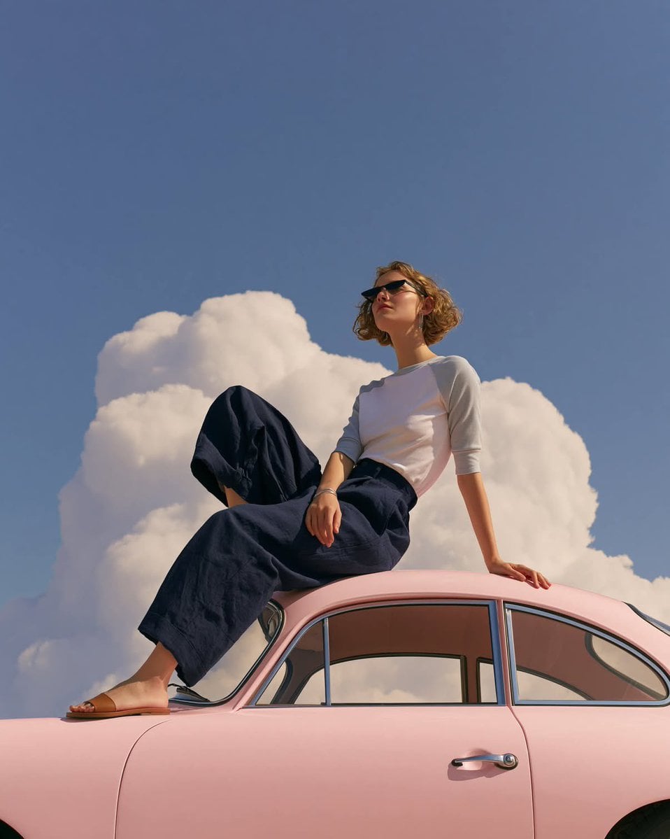 A dreamy editorial fashion photograph of a minimalist young woman sitting gracef