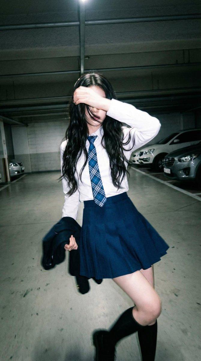 Candid portrait of a young woman in a dim parking garage, wearing a white shirt 