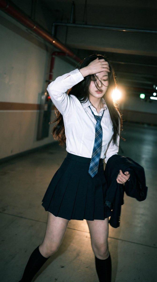 Candid portrait of a young woman in a dim parking garage, wearing a white shirt 